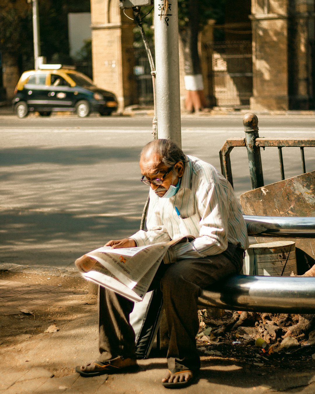 Elderly local man reading a newspaper on a bench